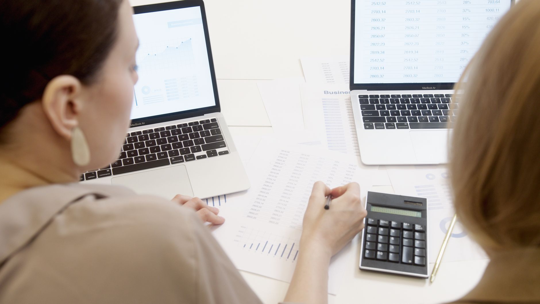 Person working with a laptop, papers and calculator